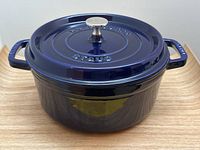 Front view of dark blue Staub Dutch oven with lid on wooden surface