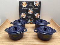 All four mini ovens arranged on a surface with the Staub cookbook standing behind