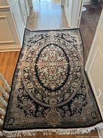 Overhead view of full rug laid on hardwood floor showing entire floral medallion pattern and fringed edges