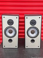 Front view of both speakers on table against red background