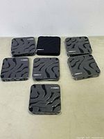 Photo showing seven black T95Max TV streaming boxes with a waved pattern and brand name on the top surface, arranged on a surface.