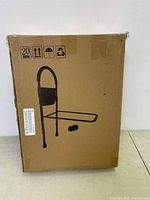 Front view of box showing bed rail with vertical handle and pouch for items, illustration of product on cardboard box.