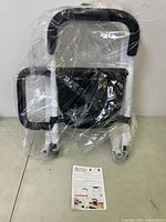 Photo showing the folded bed rail in plastic packaging along with the installation instruction manual.