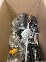 Photo showing various hardware parts including black wall hooks, curtain rod components, screws, and fittings.