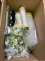 Photo showing the floral decoration, plastic containers, and black strap headlamp inside a box.