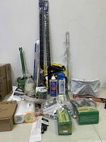 Full view of all household accessories and hand tools laid out on a table including boxed items, adhesive, chain, and tubing