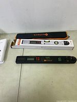 Neoteck digital angle finder gauge with control buttons, LCD screen, and built-in bubble level. Includes original box, instruction manual, and black-orange carrying case.