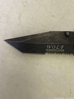 Close-up of the serrated blade marked with 'WOLF WILDLIFE COLLECTION' showing the blade shape and condition.