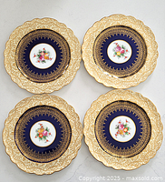 Four antique English George Jones & Sons cabinet plates arranged top-down, showing full design featuring gilt floral scalloped edges and floral center on navy background.