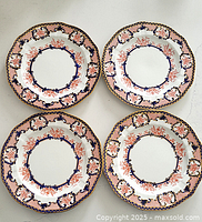 Four octagonal Royal Crown Derby dinner plates with Imari pattern arranged on a white surface.