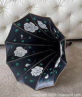 Top view of the black phonograph horn showing white rose floral pattern and green leaves on multiple panels with gold outlining.