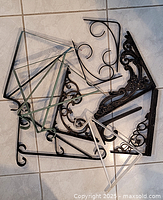 All assorted metal brackets arranged on the floor showing various decorative and utilitarian styles.