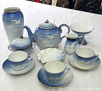 Full view of the dessert set laid out, showing all items including teapot, sugar bowl, creamer, vase, basket shaped dish, pedestal bowl, and three cup & saucer sets.