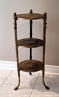 Full view of the 3-tier brass stand with visible decorative engravings and structure