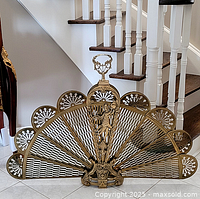 Full front view of folding brass fan fireplace screen against staircase