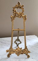Front view of the 10-inch gilt metal easel showing intricate scroll and floral design on fine metalwork.