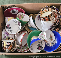 Top view of assorted vintage porcelain cups and saucers packed tightly in a box, various floral patterns and colors visible