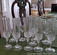 Photo showing a group of 10 crystal stemware glasses arranged on a green cloth, featuring various diamond cut and fluted designs.