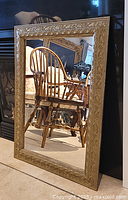 Mirror standing upright showing reflection of wooden chair and surrounding room.