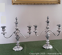 Full view of both candelabras side by side on green cloth against wall