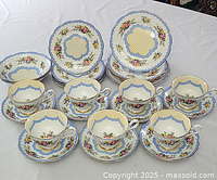 Overall view of the tea and dessert set showing cups on saucers with dessert plates in background.