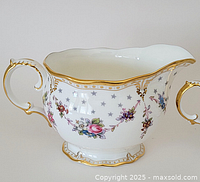 Front angle view of creamer showing floral garland motif and gold trim