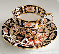 Teacup placed on matching saucer displaying intricate multicolored floral and geometric Imari design with gold accents.