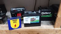 Image showing 4 batteries on shelf: Motomaster, Interstate, DieHard, and Rayovac lantern battery