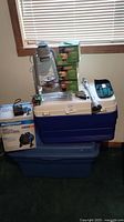 Photo shows ceramic barrel heater, Radio Shack Realistic radio, Beacon lantern, replacement lantern globes, lock pouch, and stacked Igloo coolers.