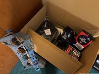 Box with metal engine gaskets, LED headlight kit boxes, and other automotive parts inside.