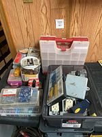 Photo showing assorted hardware and electrical supplies in plastic boxes, including Mastercraft stud finder, crimping pliers, and compartment boxes.