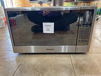 Front view of Panasonic microwave oven showing door and control panel reflecting surroundings.