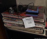 Sony Walkman WM-11 cassette player closed with headphones and harmonica on top of stack of vinyl records