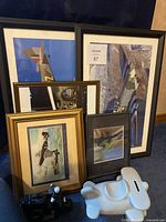 Framed airplane-themed prints stacked together with white ceramic airplane piggy bank in front.