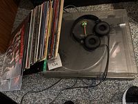 Turntable with stack of vinyl records and headphones on top