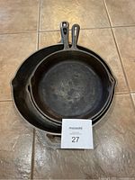 Three cast iron skillets stacked together from above, showing sizes and handles.