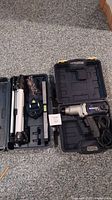 Photo showing the laser level, tripod, and carrying case on the floor demonstrating the contents of the measurement tool set.
