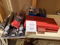 Shelf view showing red case with magnetic socket organizer and blue Mastercraft drill bit case, along with additional drill bits and tools