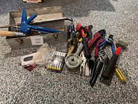 Overview of toolbox, caulking gun, wrenches, screwdrivers, scraper blades, and small hand tools arranged on carpet