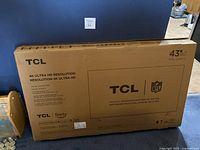 Front of unopened TCL 43″ TV box showing brand, NFL partnership logo and 4K Ultra HD label.