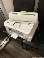 View of Brother printer with paper tray extended and Scotch laminator on top showing front panel with brand and controls.