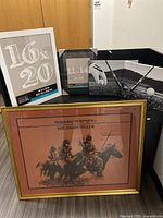 Lot contents displayed on floor and shelf: large Howard Terpning framed print, two black framed golf pictures, two unused frames (16x20 and 11x14)