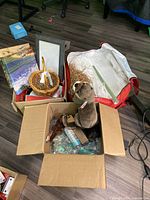 Photo shows various items including a box filled with white tissue paper, a basket, a stuffed otter, and other miscellaneous items on the floor.