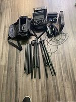 Full view of studio lighting panels, computer speakers, speaker tripod parts, and carrying bags on floor.