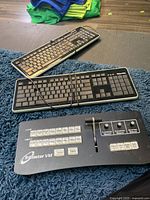 NewTek TriCaster VM switcher with two standard wired keyboards on a blue rug.