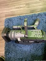 Side view of Sony HDR-FX7 camcorder showing lens and hand grip on blue textured surface.