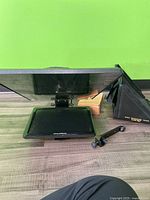 Front view of Prompter People teleprompter with 23 inch glass and attached monitor, hood, and mounting arm visible.