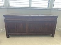 Front view of wooden chest showing paneled sides and low curved feet
