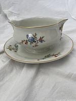 Porcelain dish and underplate, side view of dish showing floral side decoration and gold trim
