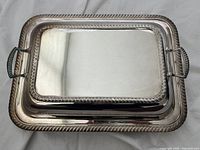 Rectangular silver plated serving dish with lid, showing rope twist decorative border and twisted handles on lid sides